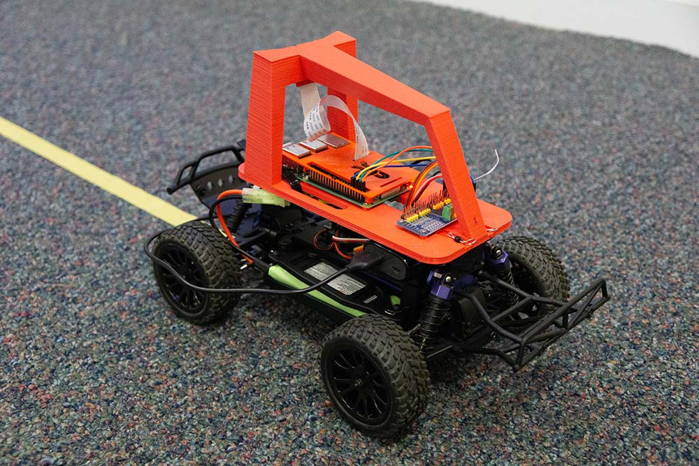 Small Donkey Darlings autonomous research car with exposed electronics and an orange frame