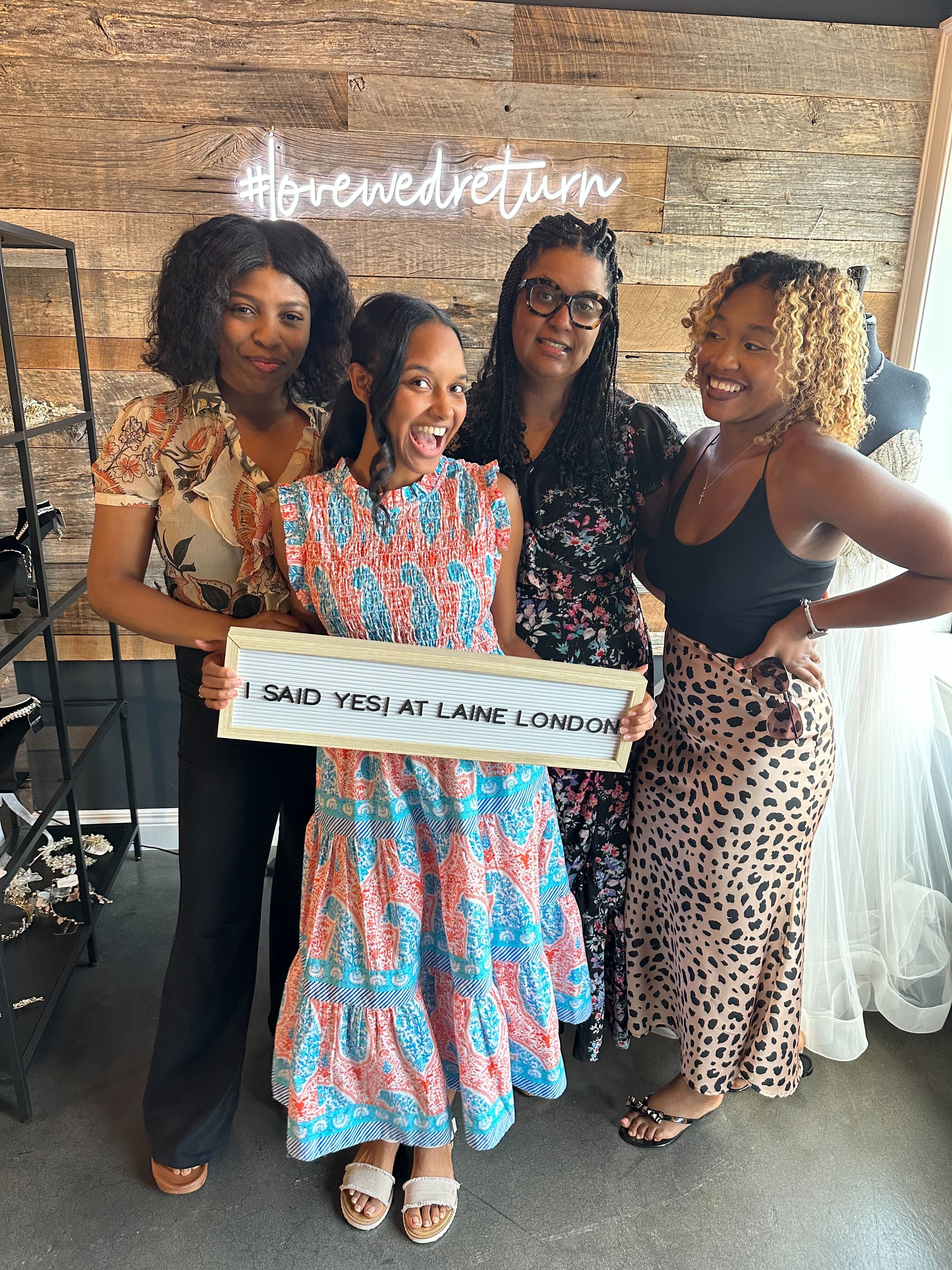 A bride and three companions celebrate after selecting a dress at Laine London