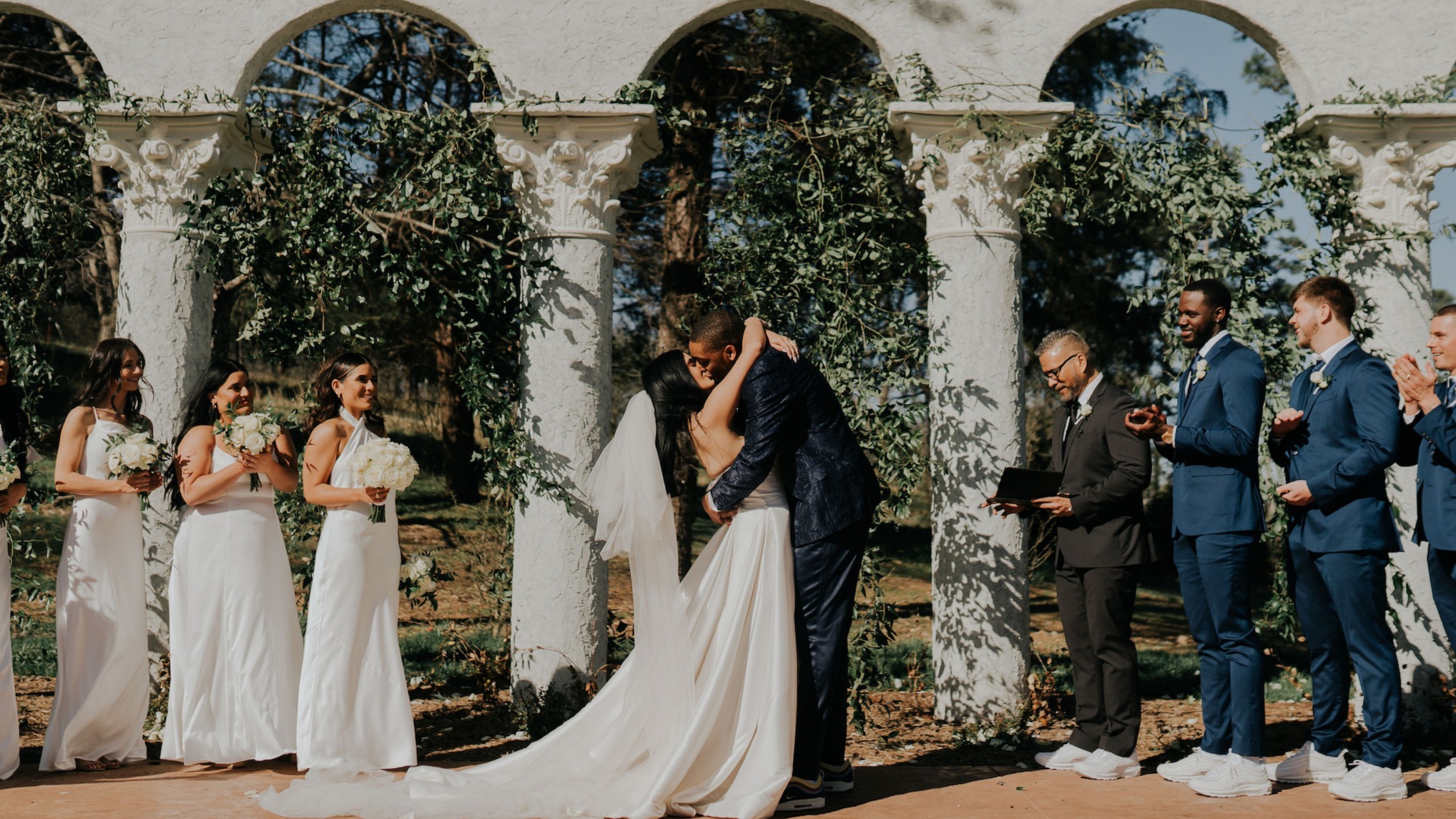 A Laine London bride and her partner kiss at their outdoor wedding