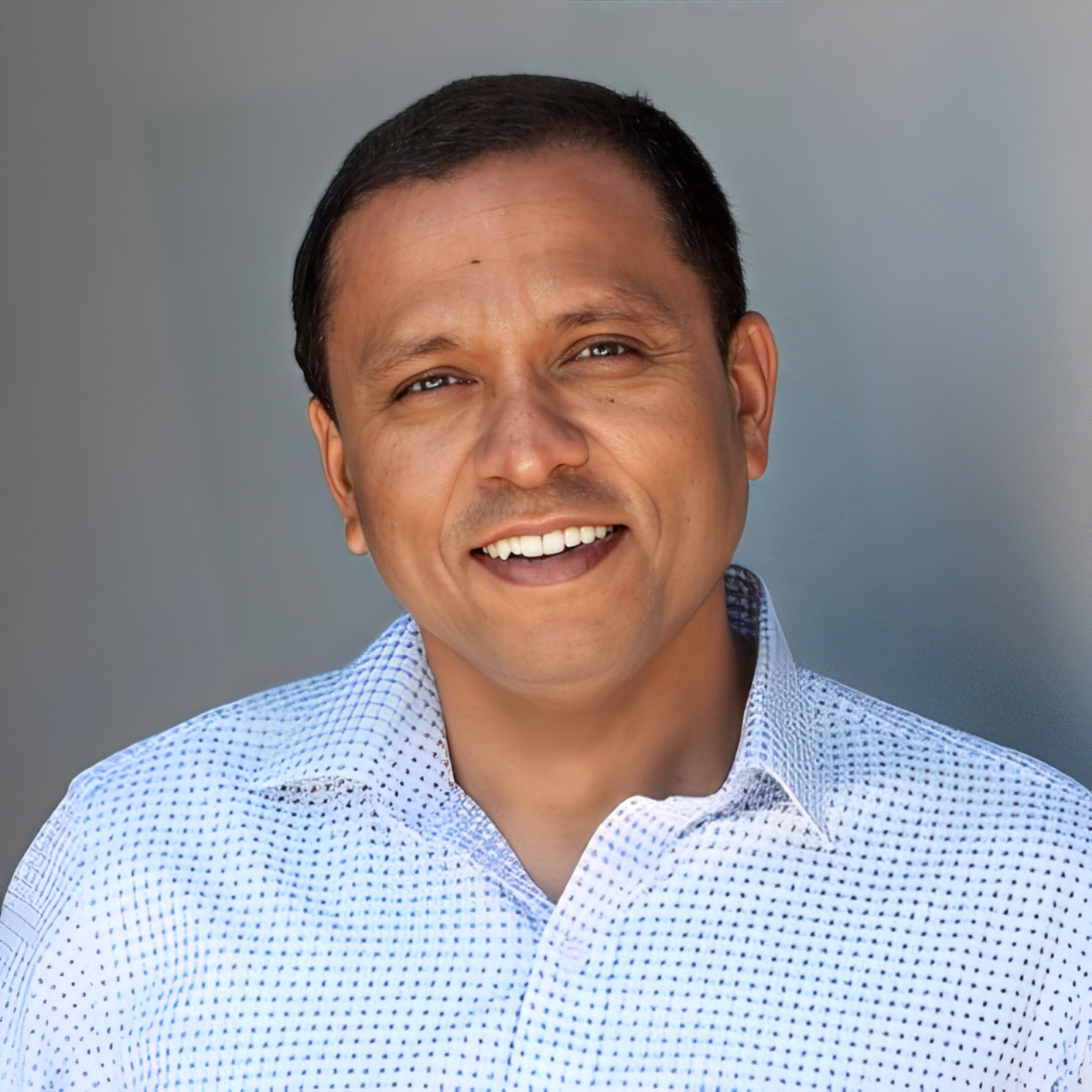 Lakshman Rathnam smiling in a patterned shirt against a neutral background