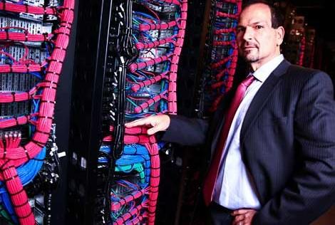 Lance Crosby standing beside racks of servers and bright network cables at SoftLayer