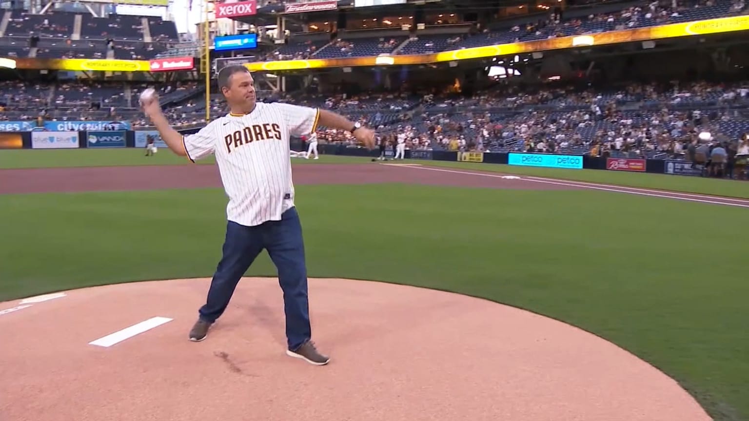 Lance Tucker in a Padres jersey throwing a ceremonial pitch