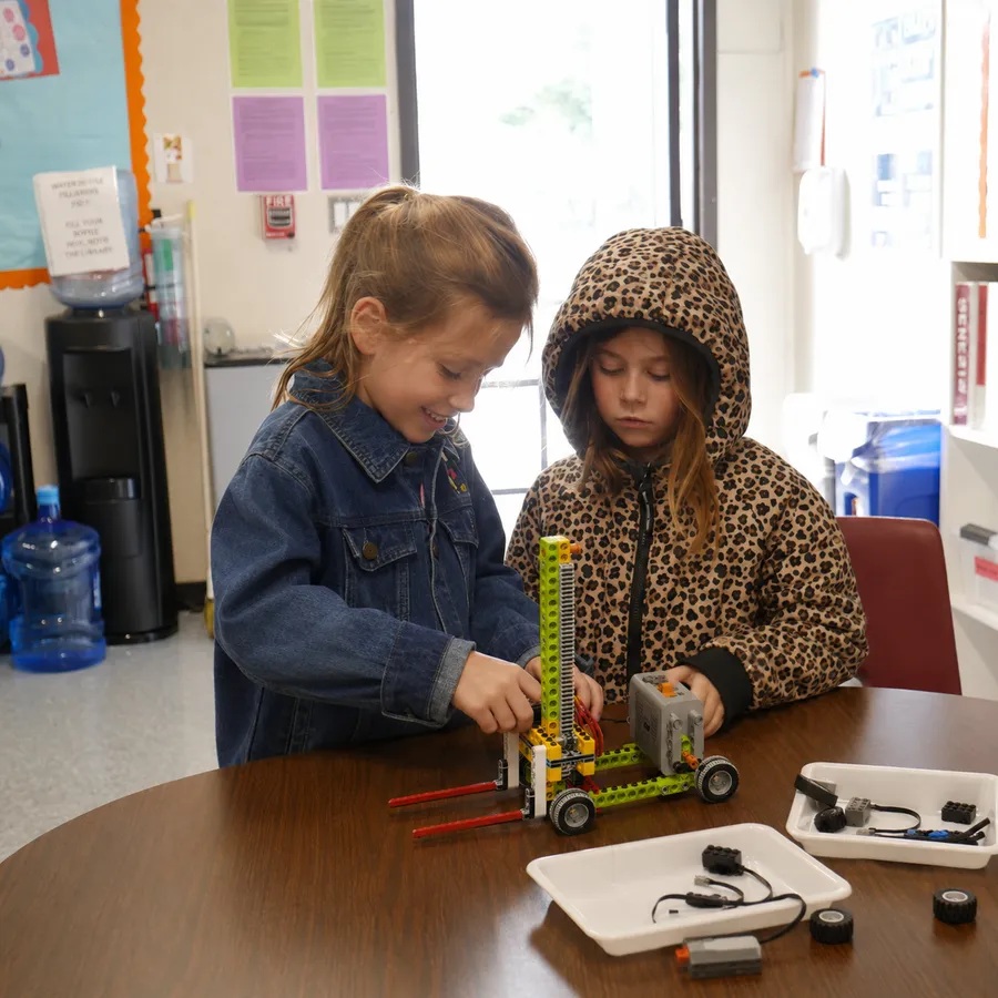 Two children collaborate on a motorized LEGO vehicle in a Lando classroom