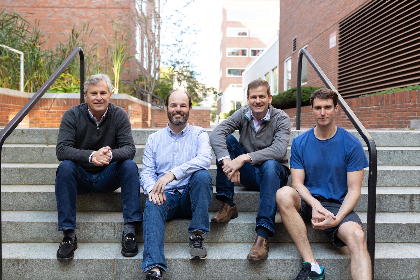 Langley Steinert, Josh Arnold, Tom Gilmore and Oliver Chrzan seated on outdoor steps near ApartmentAdvisor’s Harvard Square office in 2021.