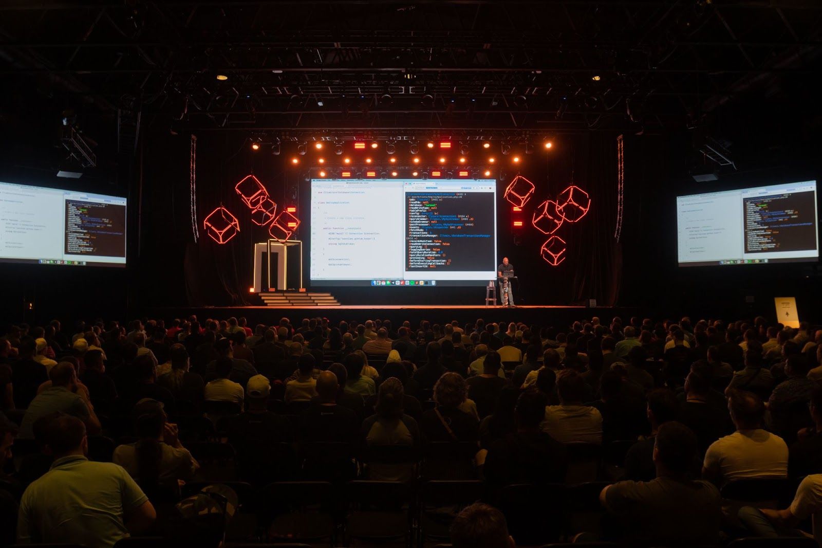 A developer presentation on a large stage before a conference audience