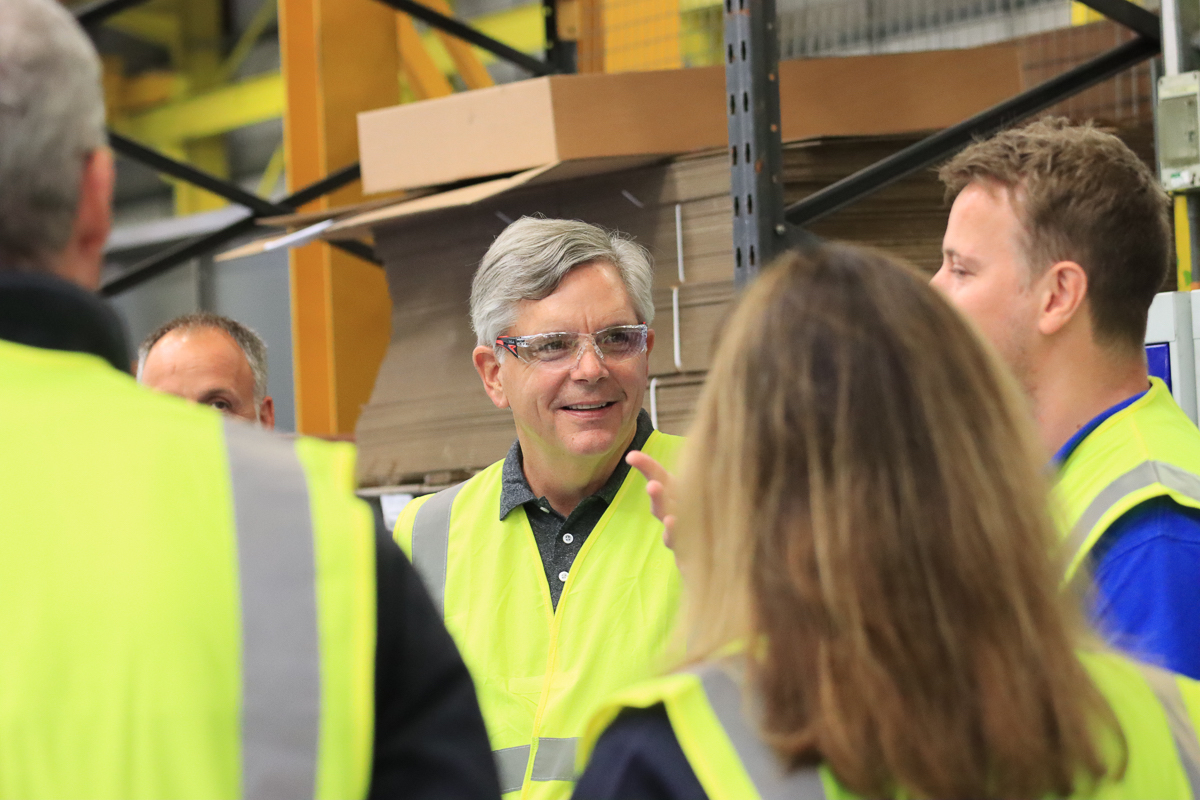 Larry Culp, wearing safety glasses and a high-visibility vest, talking with GE Aviation employees in Wales