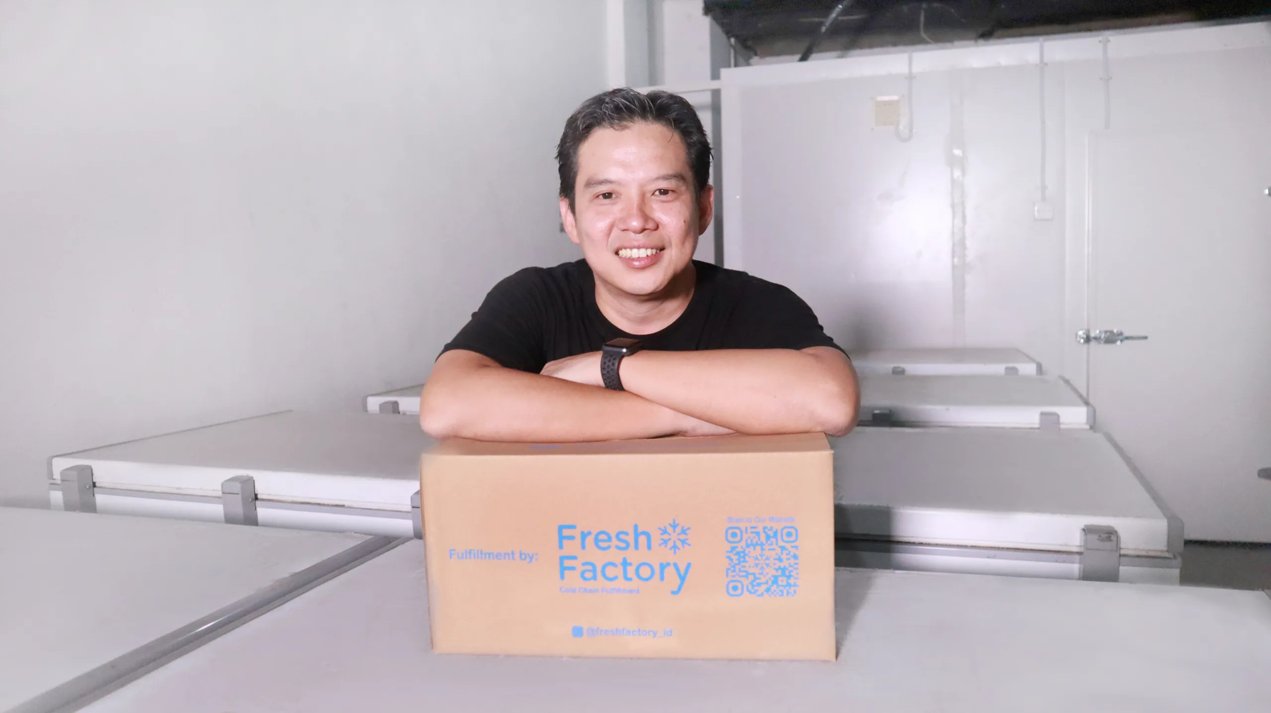 Larry Ridwan leaning on a Fresh Factory box inside a cold-storage facility