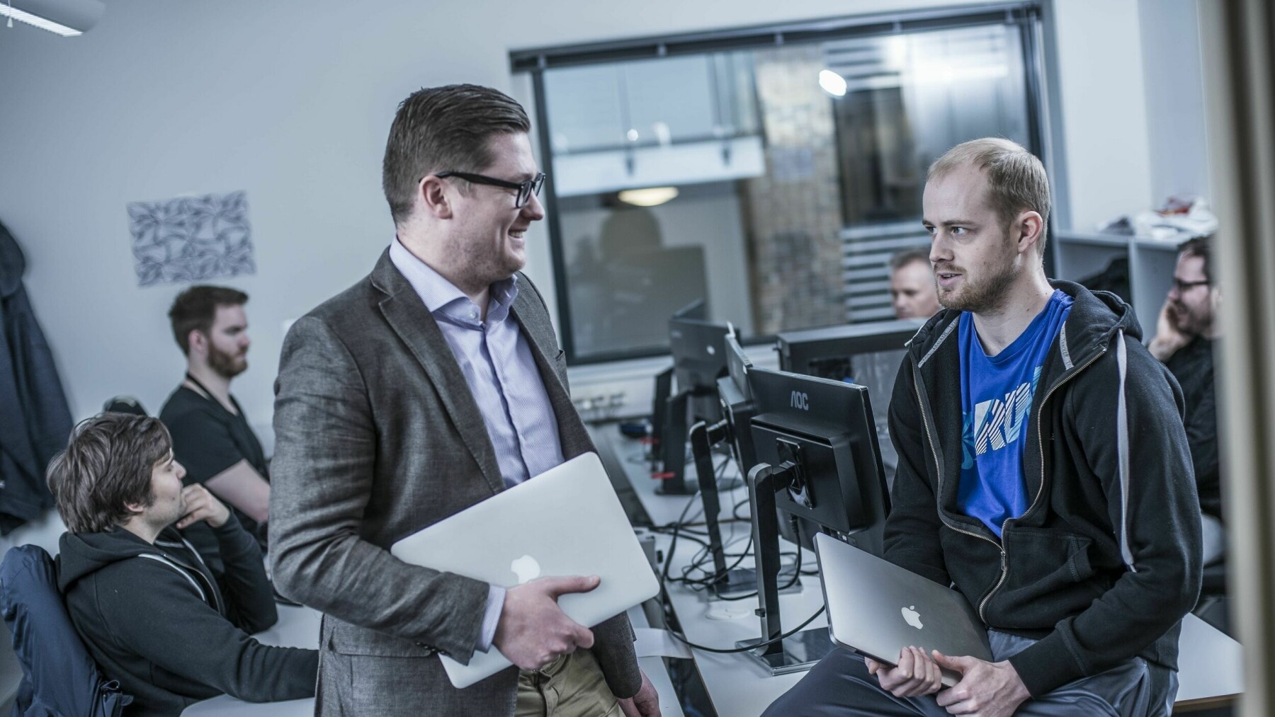 Henry Vaage Iversen, left, and Lars Ropeid Selsås, right, holding laptops in the boost.ai office