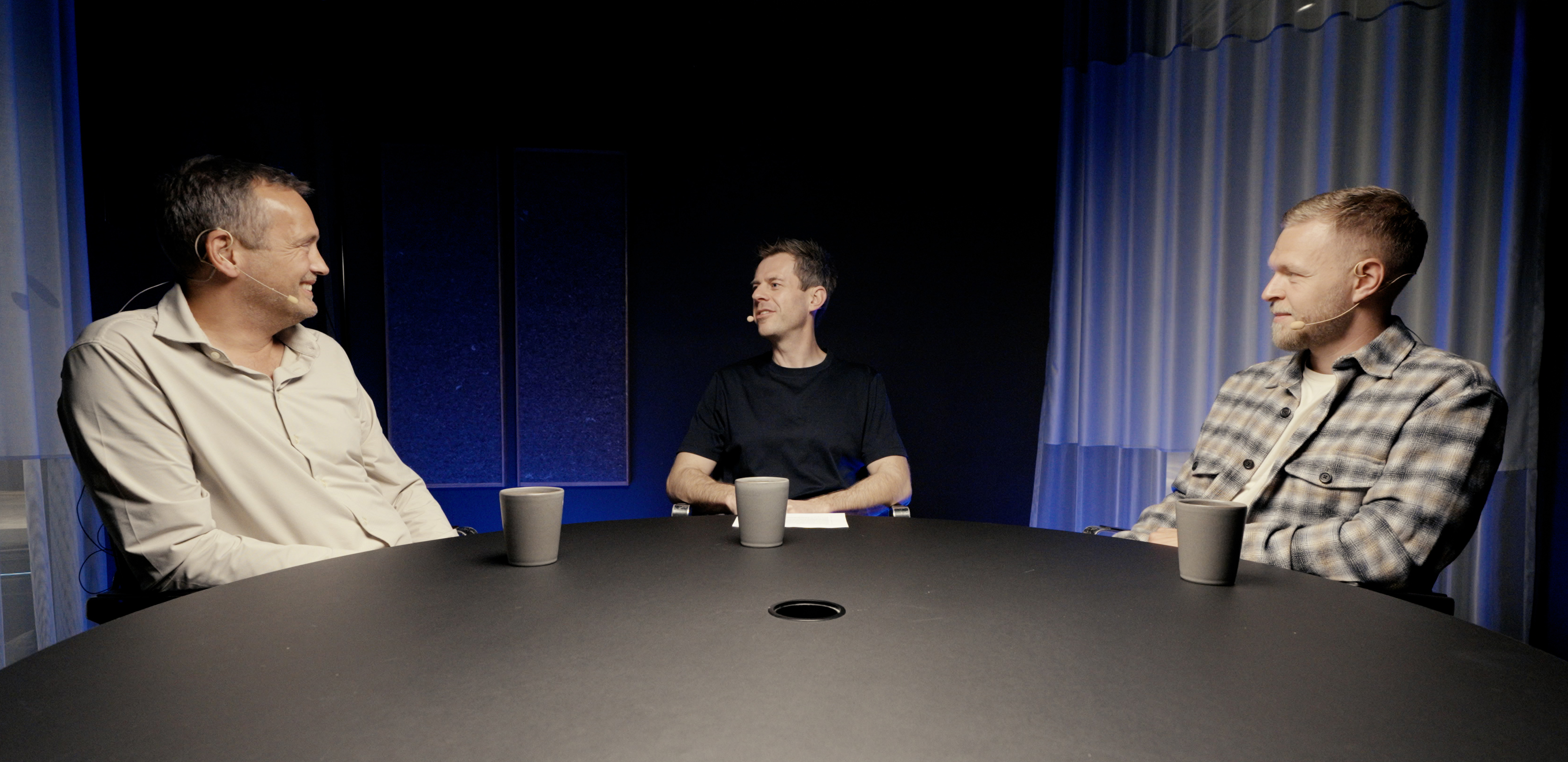 Lars Sneftrup Pedersen, Stig Larsen and Kevin Magnussen seated around a table recording the Intellis Talks Tech podcast.