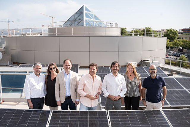 A group visiting a municipal rooftop surrounded by newly installed solar panels in Las Rozas