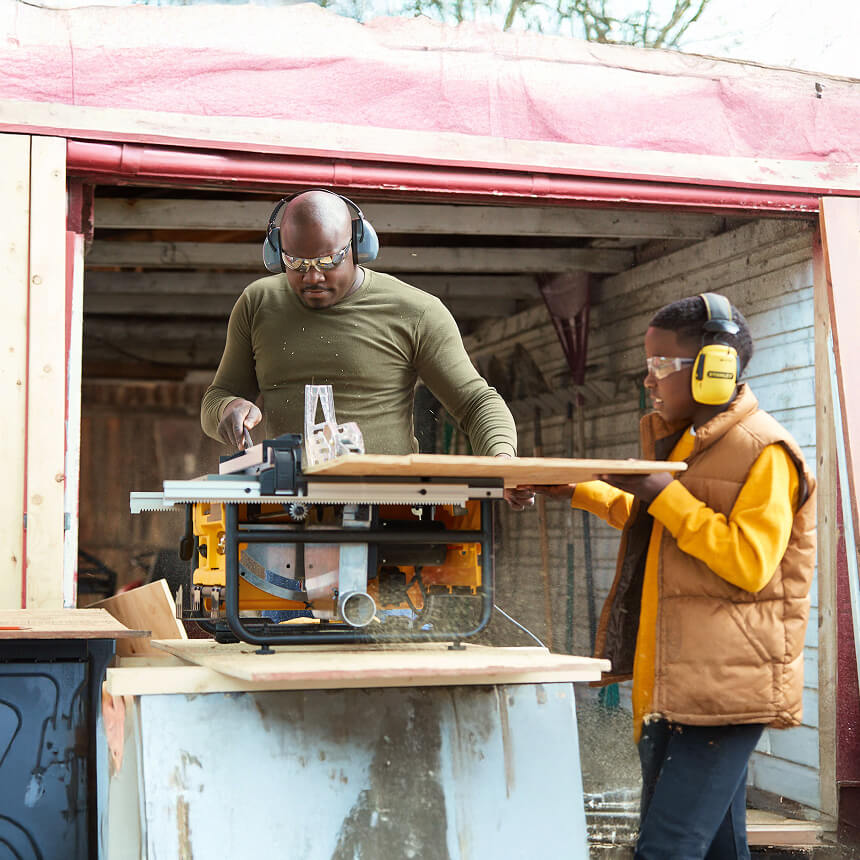 A Fleet Farm campaign scene showing two people using a table saw