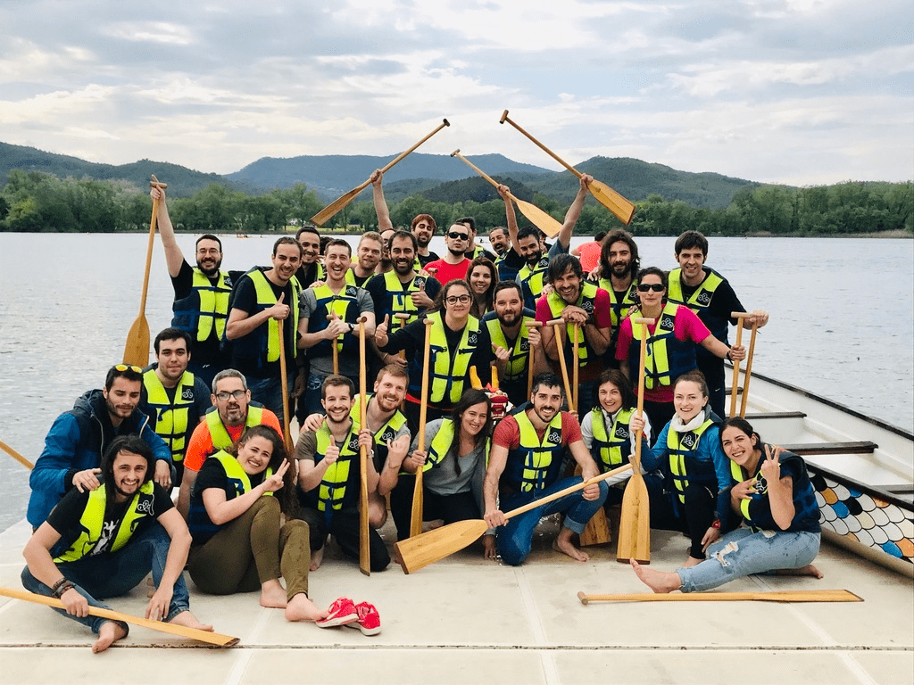 Launchmetrics employees on a lakeside team outing holding paddles and wearing life jackets