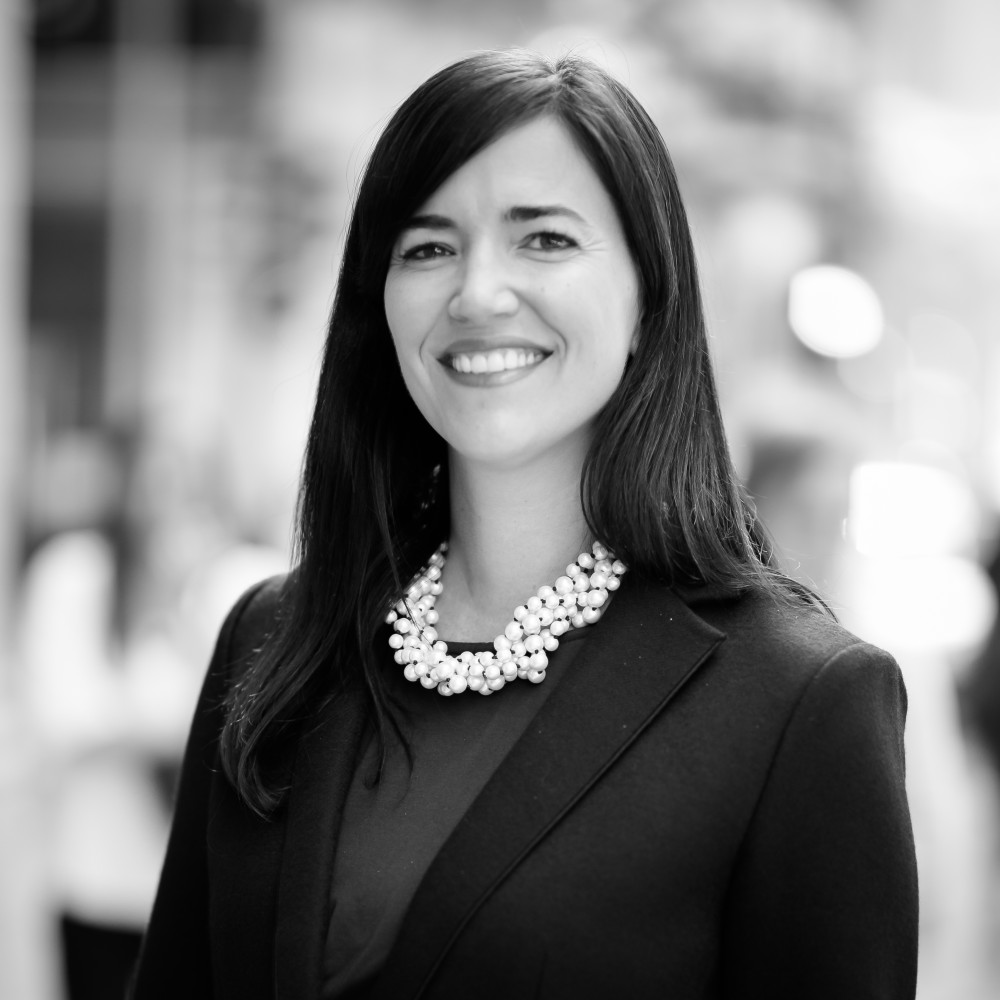 Black-and-white portrait of Laura Barger smiling in a dark blazer and beaded necklace