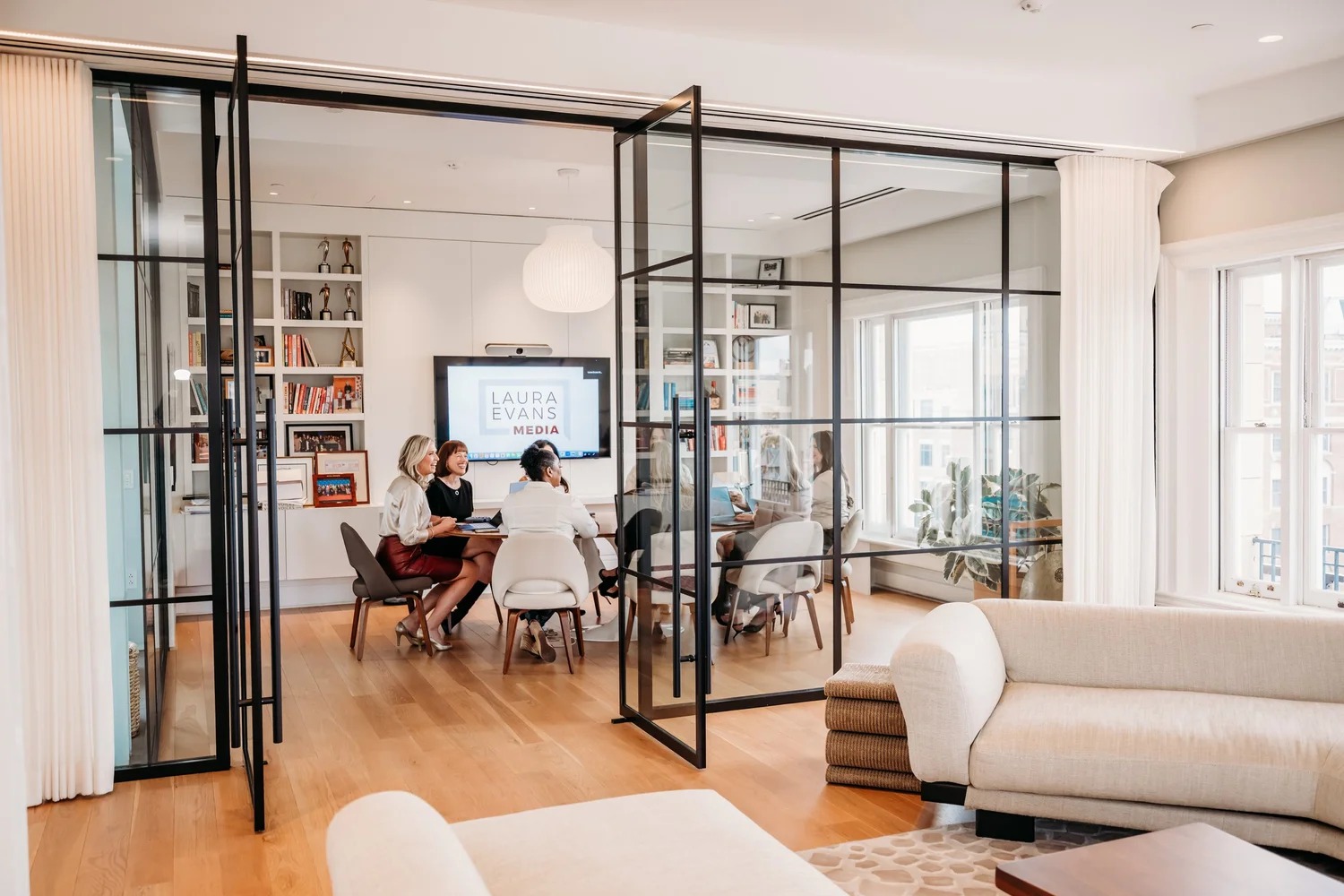Laura Evans Media team members meeting in a bright glass-walled office