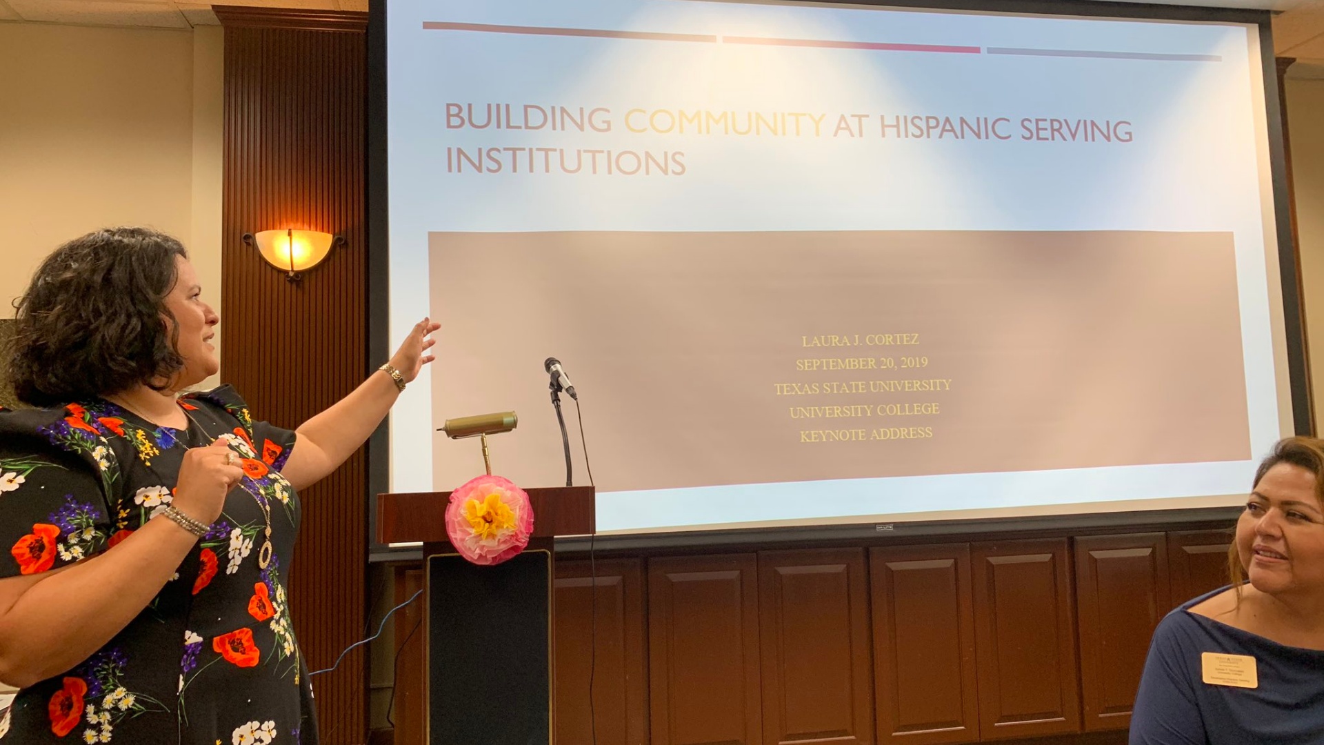 Laura J. Cortez speaking beside a presentation on building community at Hispanic-serving institutions at Texas State University