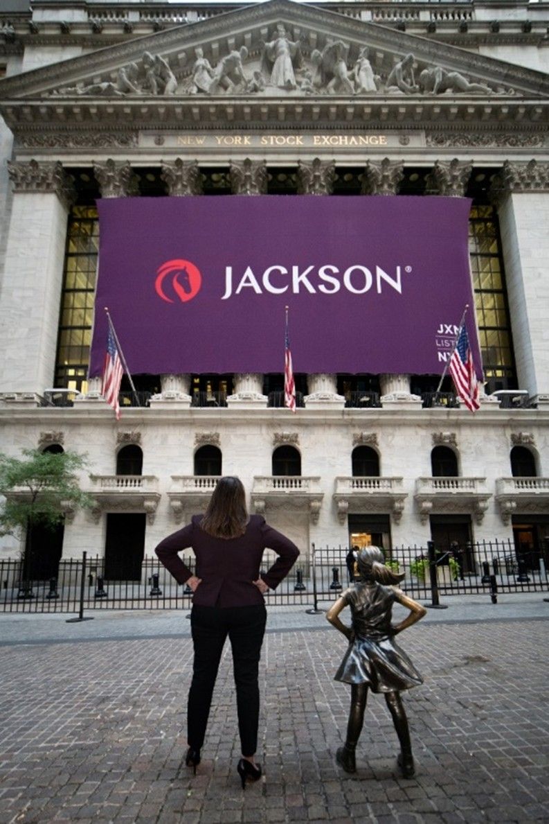 Laura Prieskorn mirrors Fearless Girl’s pose outside the New York Stock Exchange beneath a Jackson banner