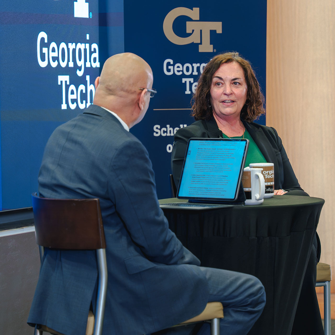 Laurel Hurd, at right, speaking with Georgia Tech Scheller dean Anuj Mehrotra at a table.