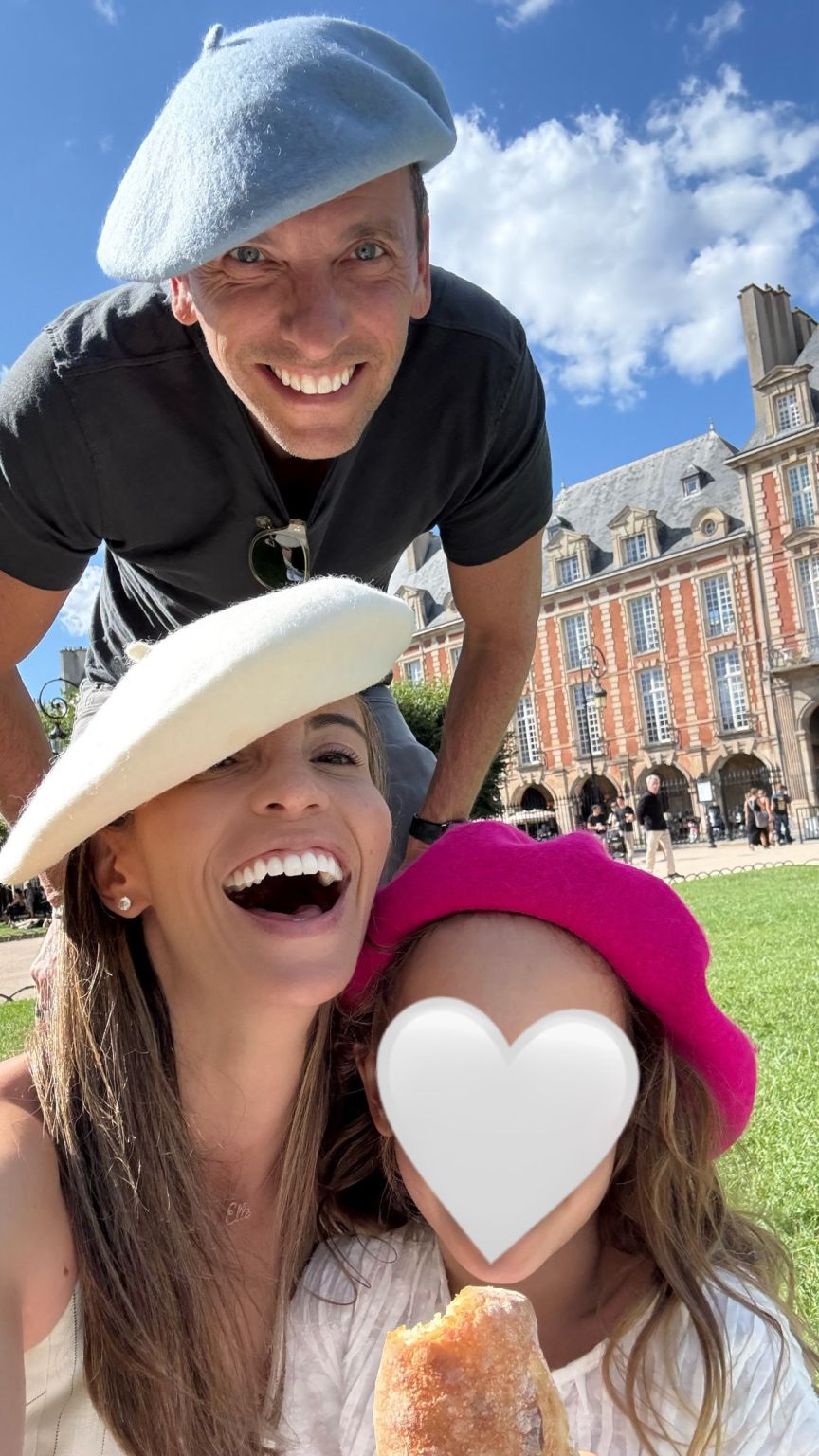 Lauren Berson smiling with her family outdoors in Paris; a heart covers her daughter’s face in the original photograph