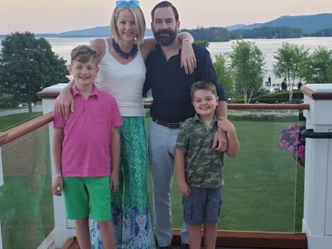 Lauren Banyar Reich standing with her husband and two sons outdoors near a lake