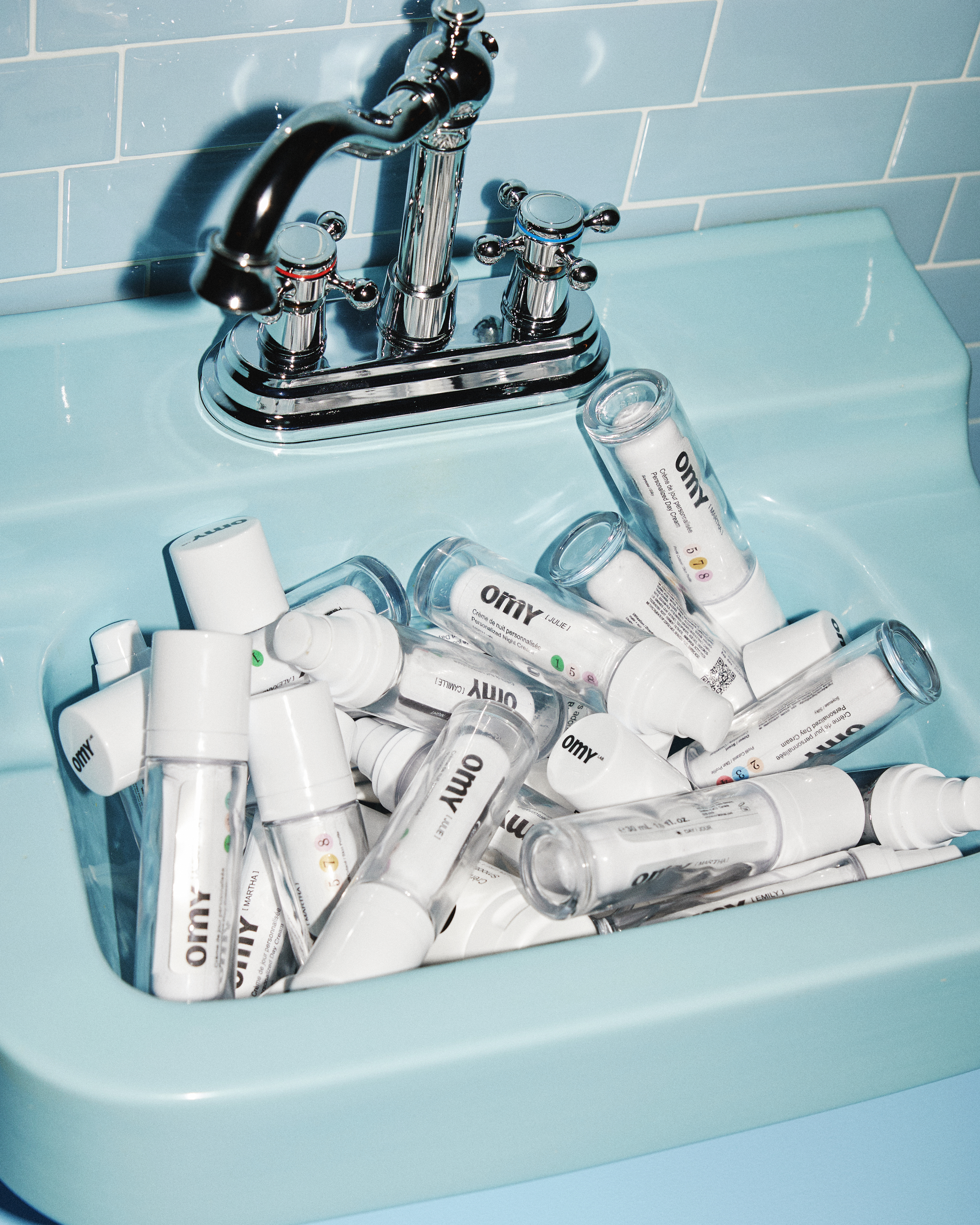 A blue sink filled with individually labeled Omy product containers