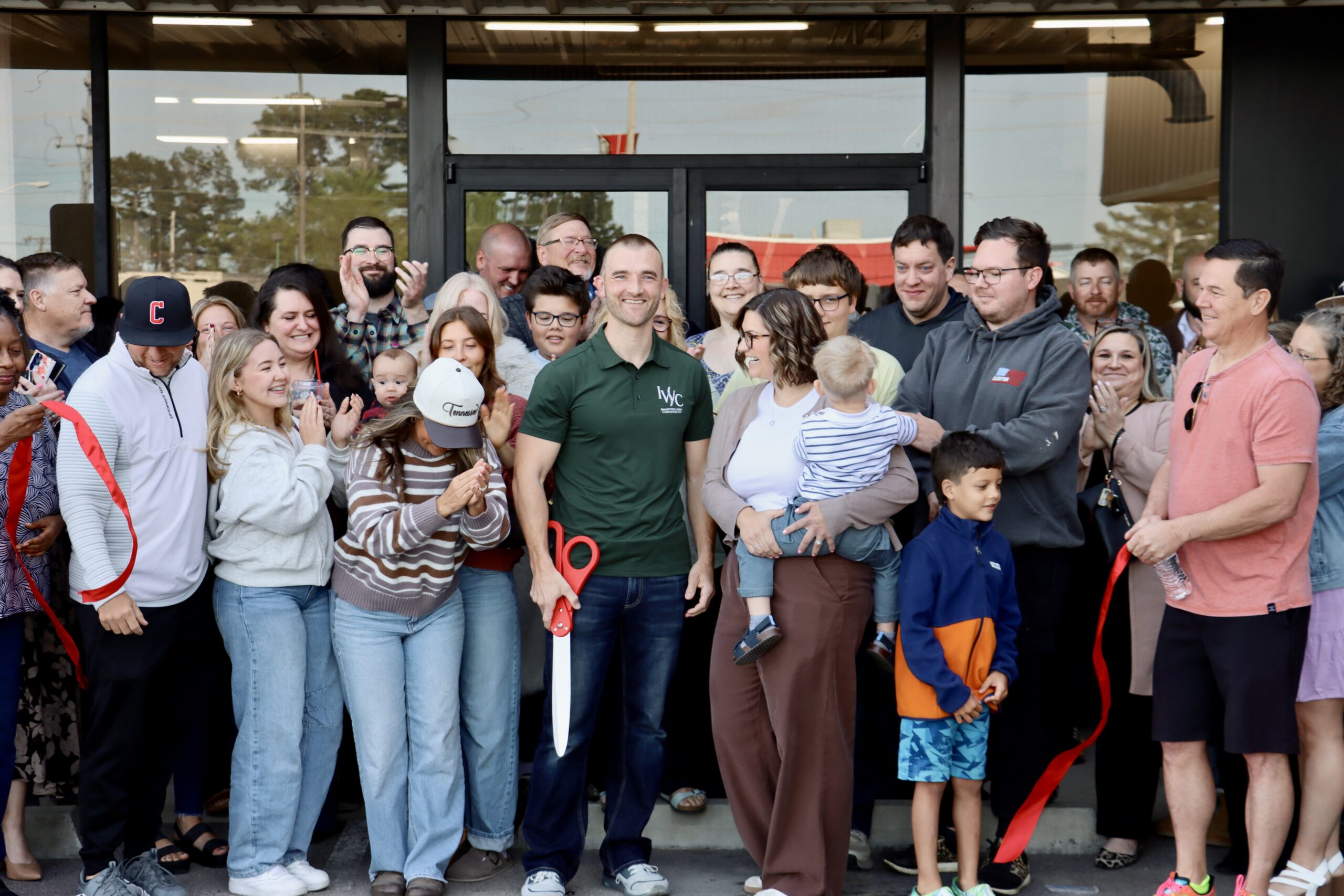 A Lawrence County business owner cuts a red ribbon while family and community members gather around