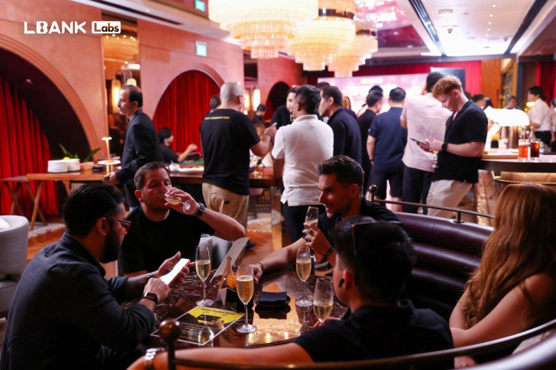 Guests talking around a table at the LBank Labs event pictured in its October 2026 announcement.