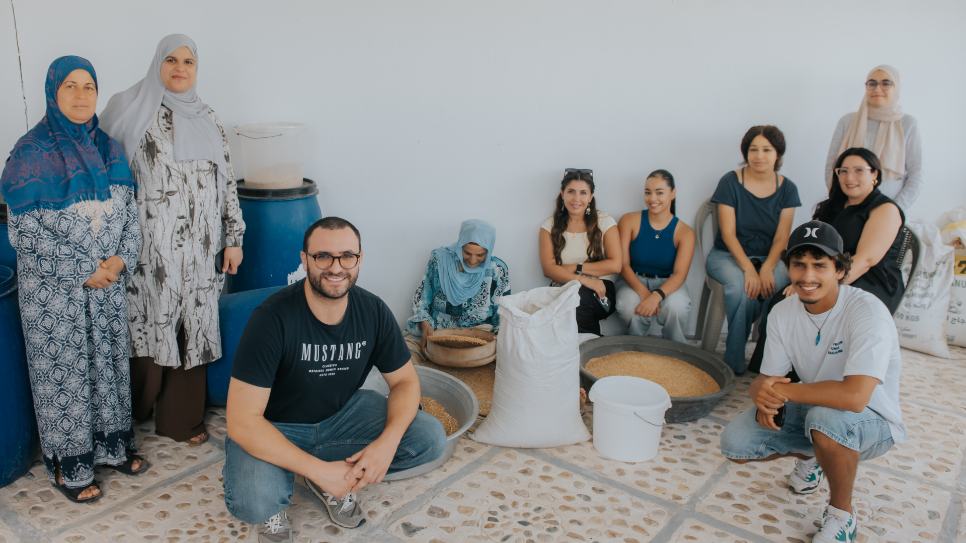 Visitors and local hosts gather around traditional food preparation during a TANIT tourism visit in Tunisia