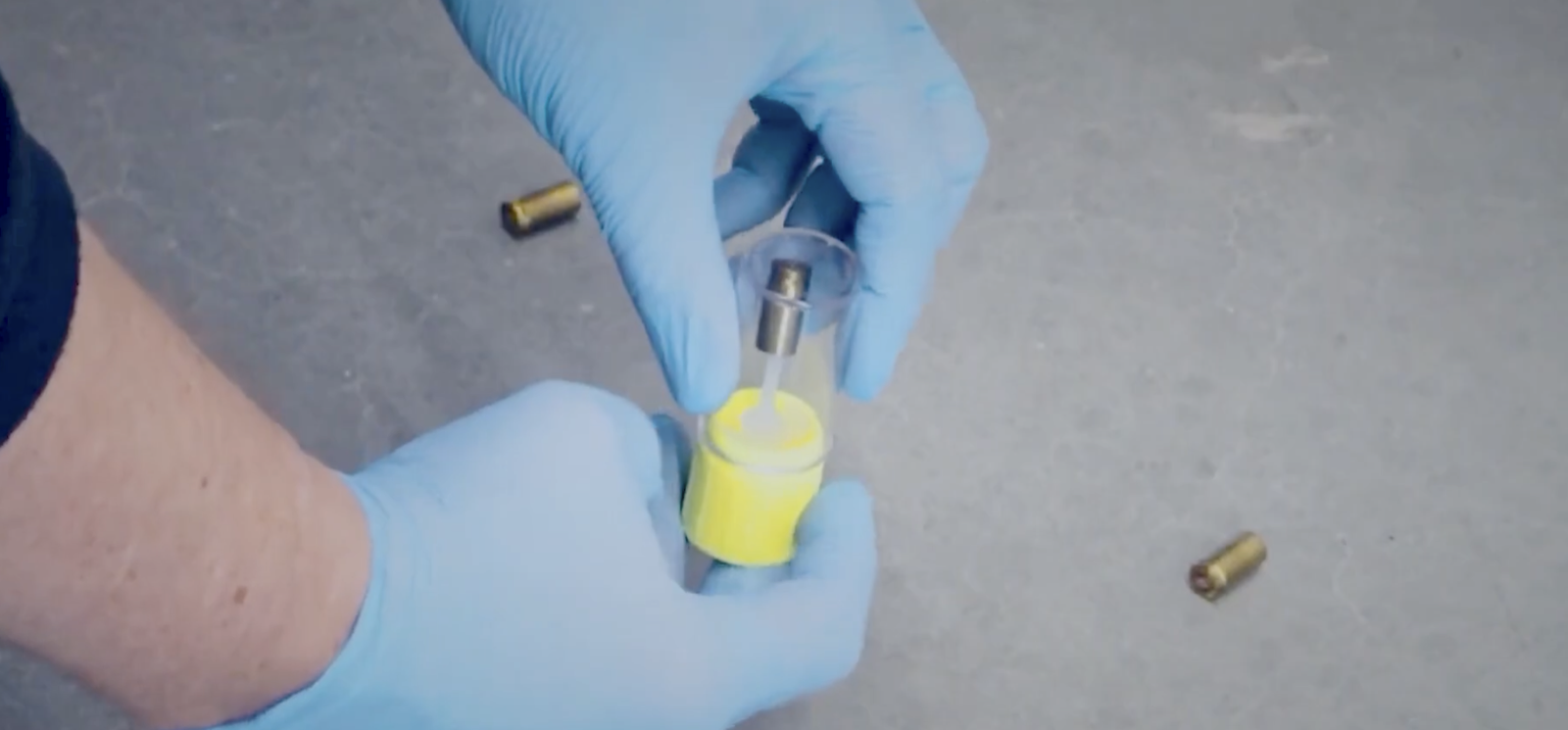 Gloved hands place a cartridge case into a ClearCase evidence tube