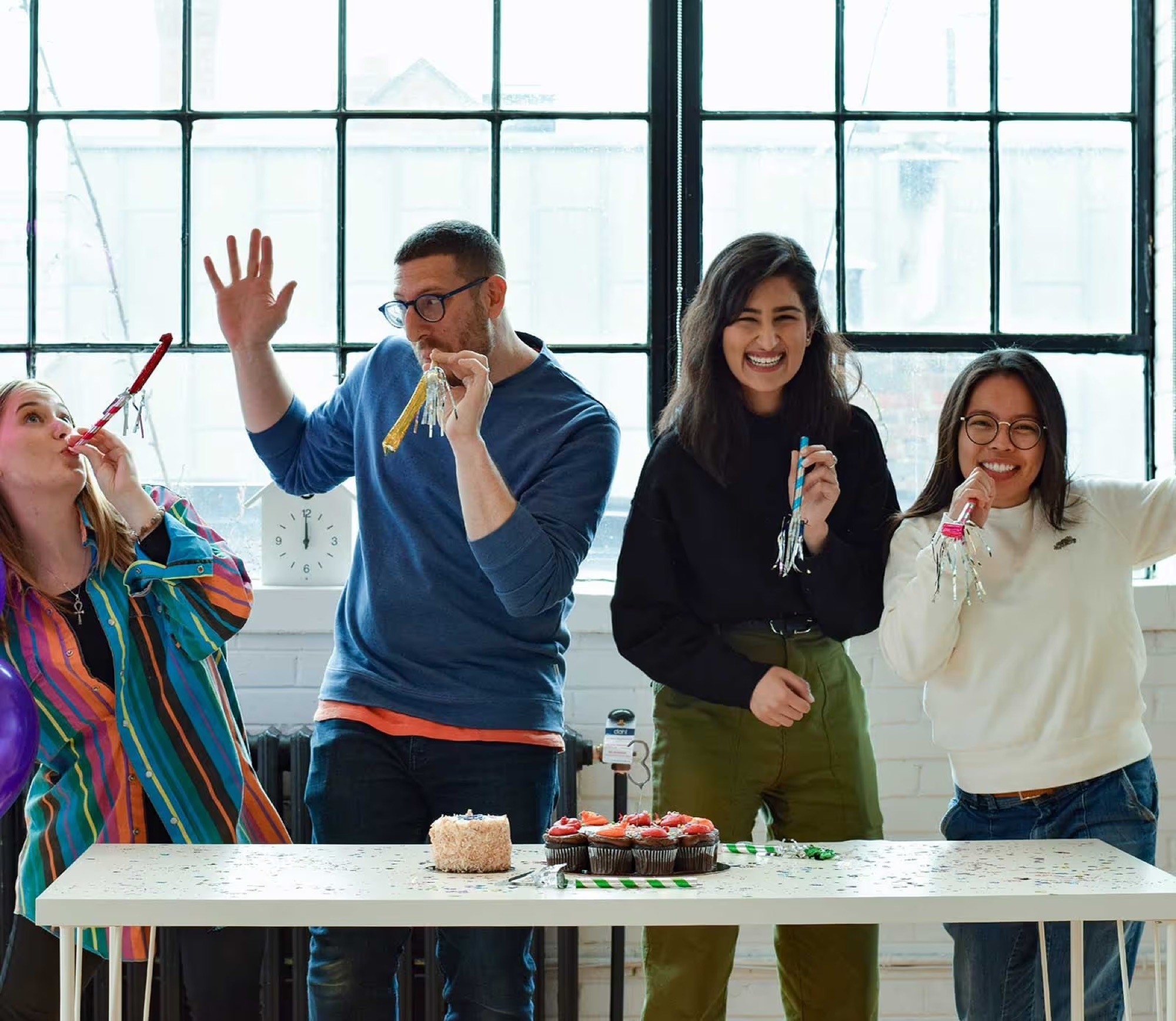 People celebrating with party blowers and cupcakes in a photograph published by LOI