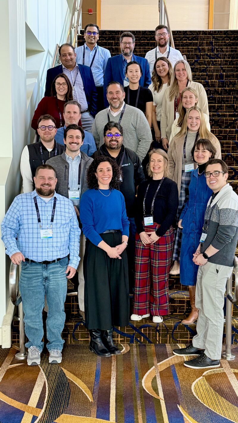 Leah Allen in a blue sweater standing with Syndigo marketing colleagues on a staircase during the company's 2026 kickoff