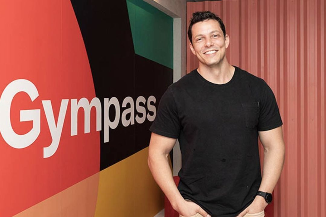 Leandro Caldeira standing in front of a colorful Gympass office wall