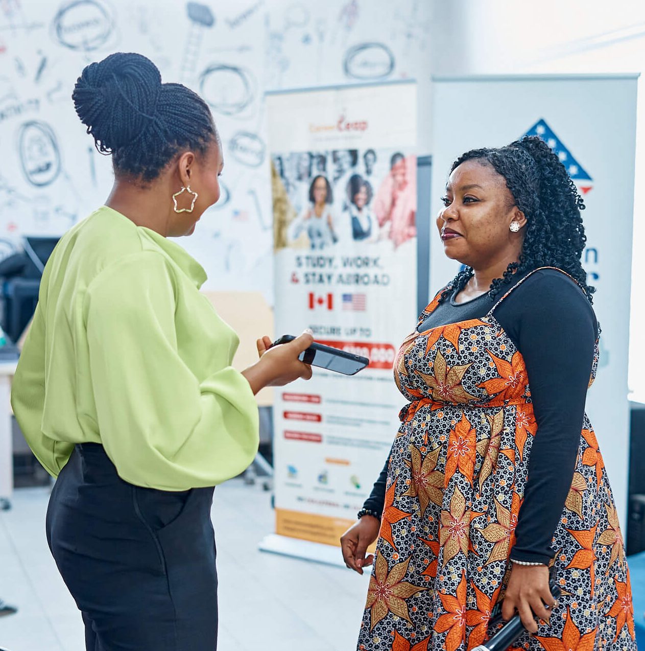 Two women speaking beside study-abroad banners in a photograph published on LeapSchool’s community page