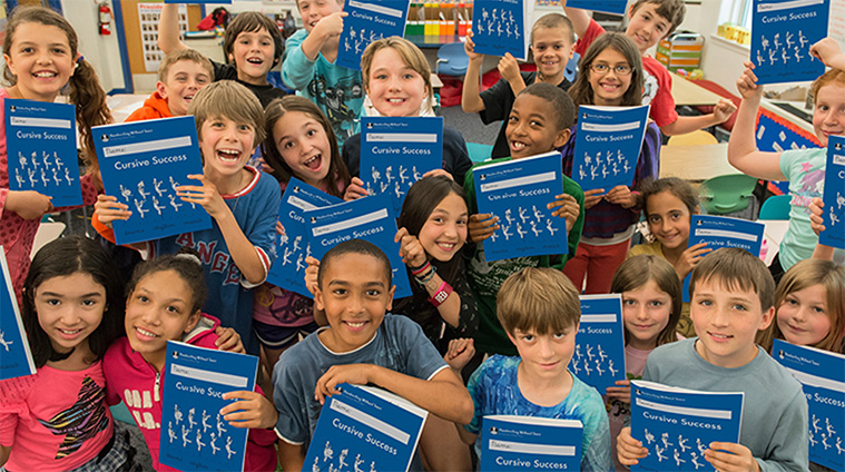 A classroom of children shows their Cursive Success workbooks.