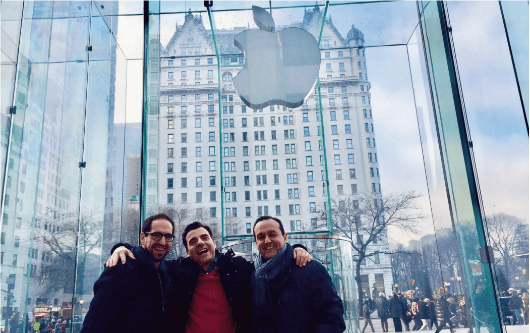 Lefteris Ntouanoglou, right, standing with two companions beneath the glass Apple store entrance