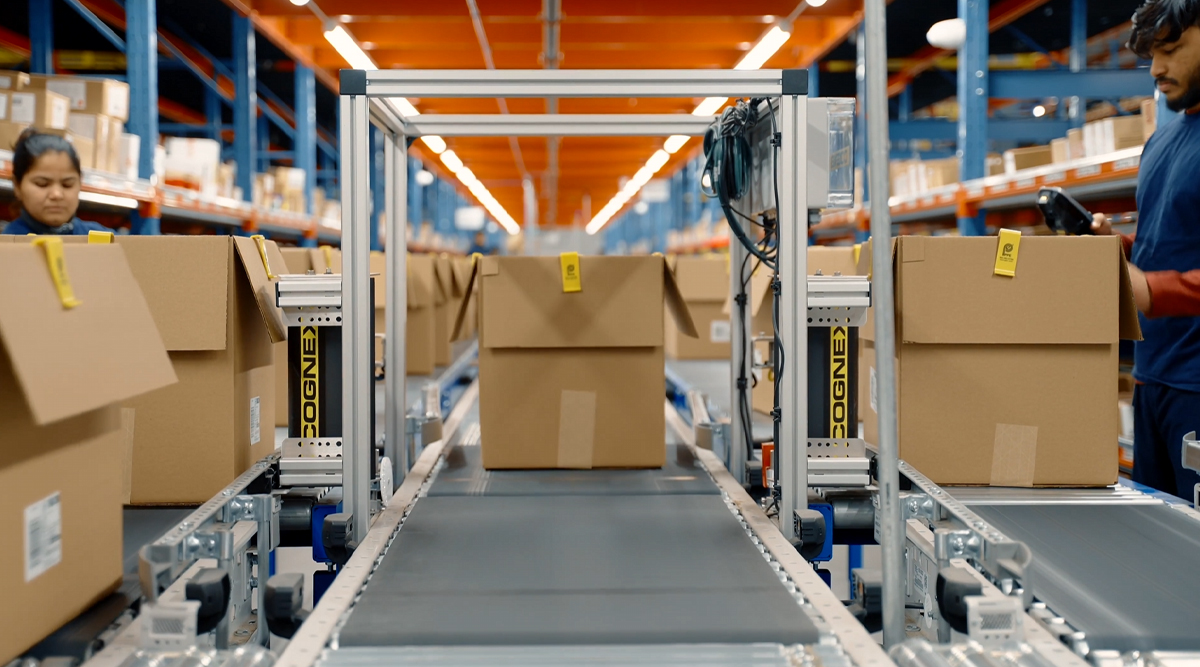 Warehouse employees working beside cartons on conveyor belts and scanning equipment
