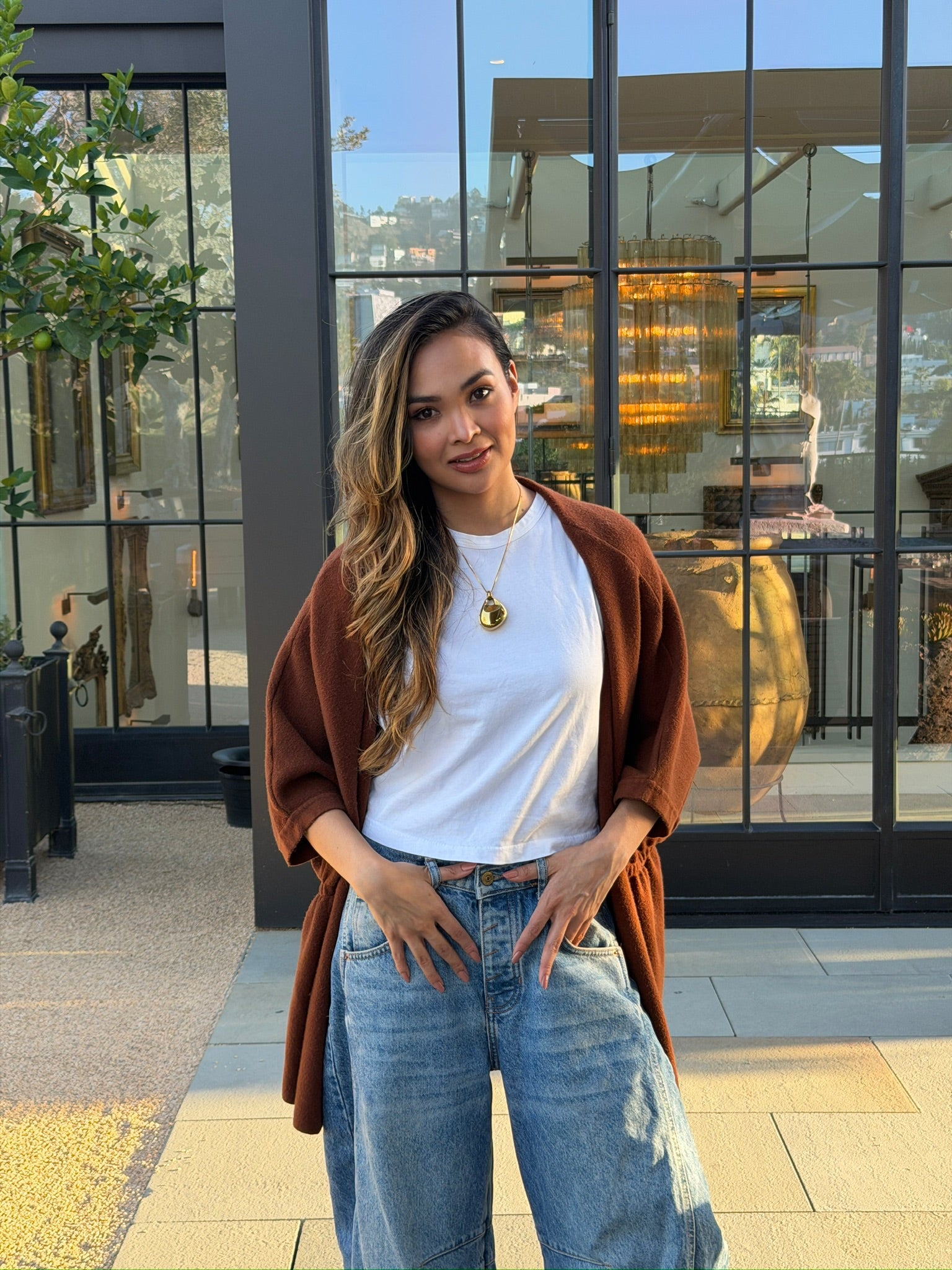 Woman wearing a gold Legend One pendant outdoors