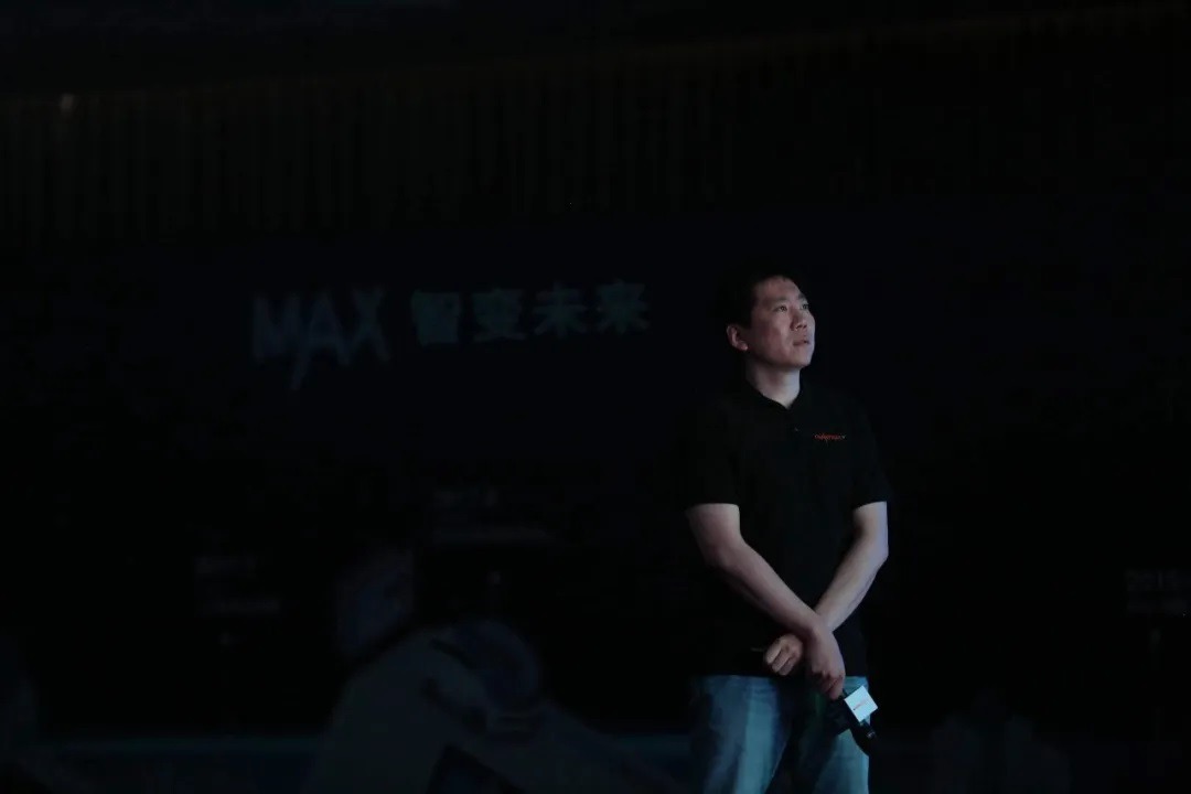 Lei Xu stands on a dark stage during a Nullmax presentation
