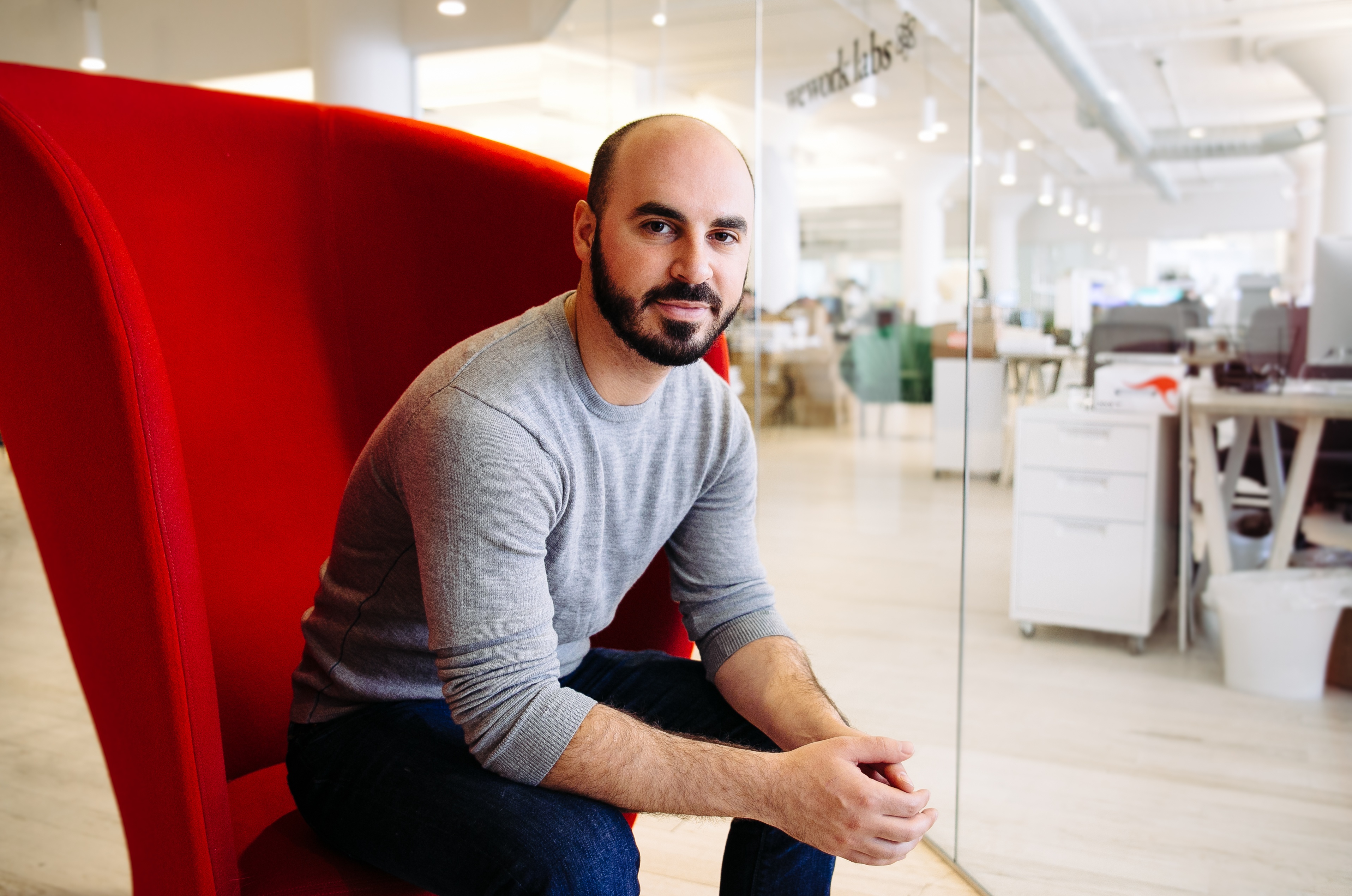 Leigh Drogen seated in a red chair in a WeWork office