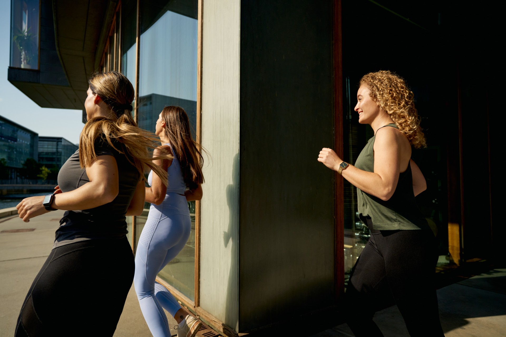 Three women in athletic clothes running outside the Lenus Copenhagen office