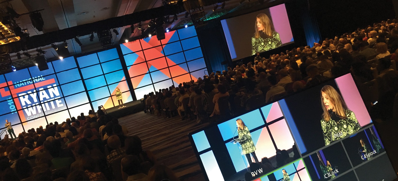 A large audience watching a speaker on stage at the National Ryan White Conference