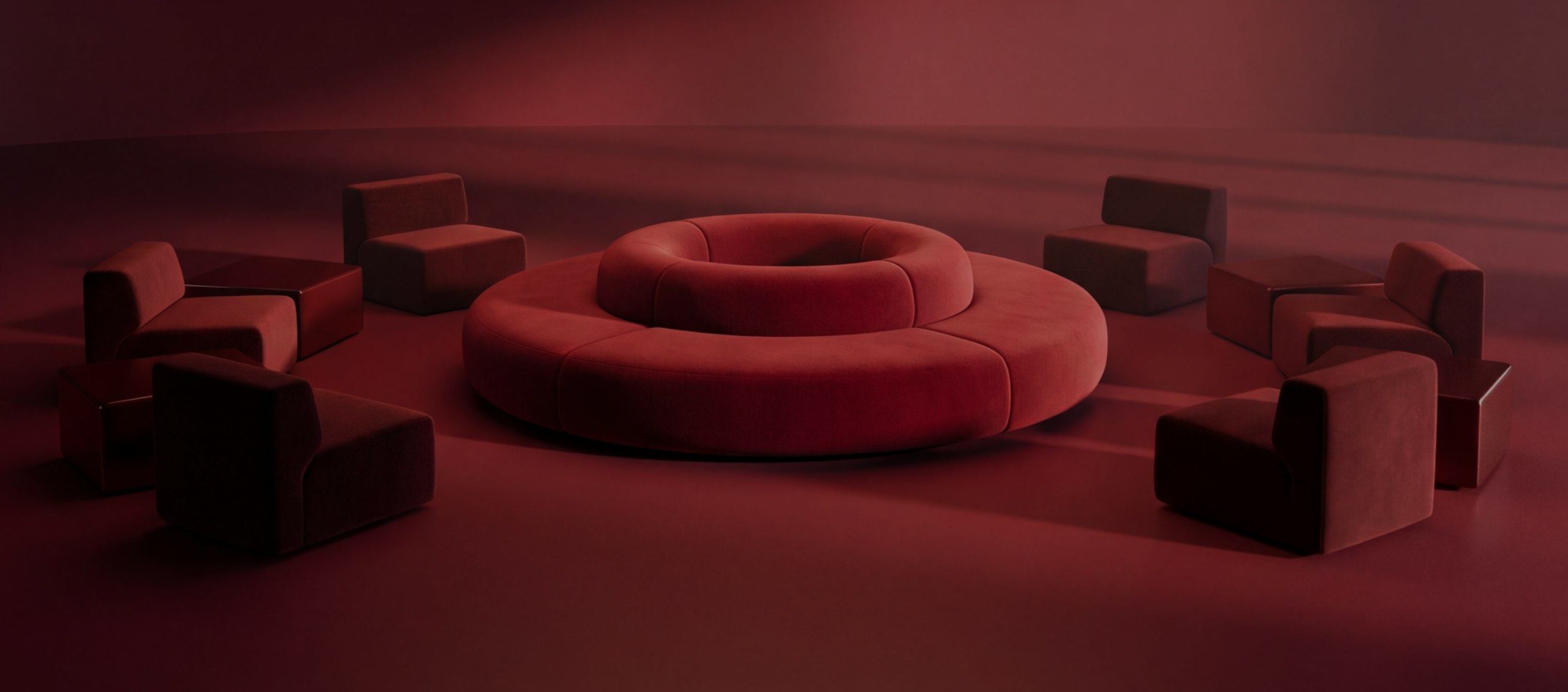 A sculptural circular red sofa and chairs in a dark red studio scene