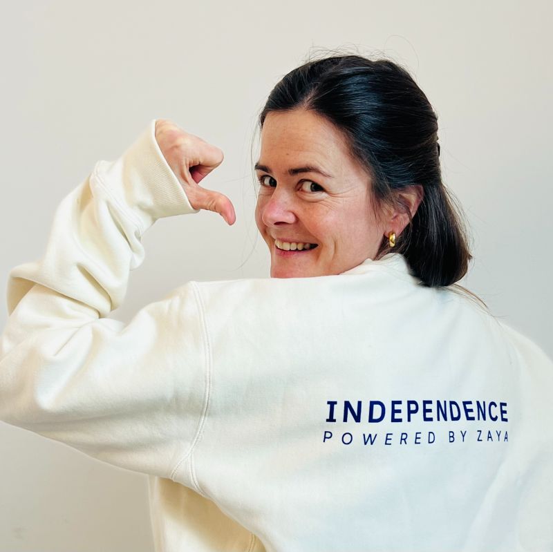 Leoni Runge pointing to the Independence Powered by Zaya lettering on her sweatshirt