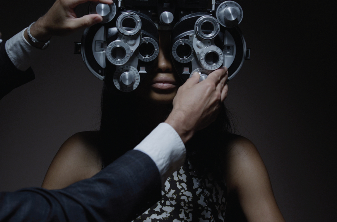 A model looking through an optometry instrument in a dark fashion campaign image