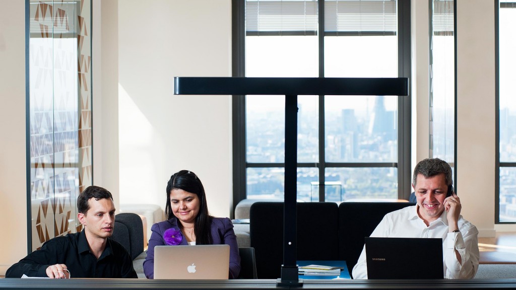 People working with laptops at a shared table inside Level39, in an archival photograph