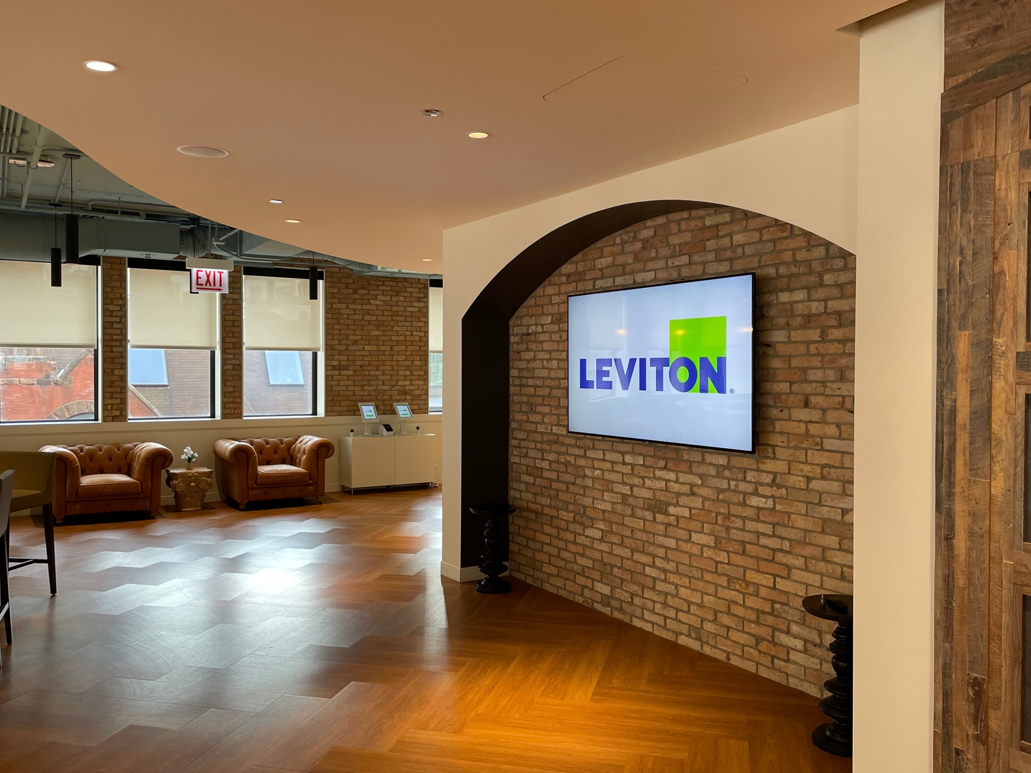 Leviton interior with exposed brick, seating and the company logo on a wall display