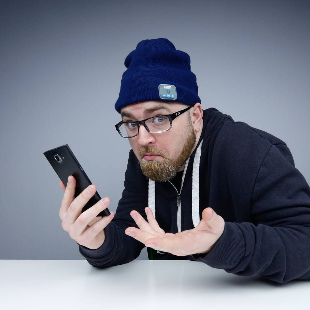 Lewis Hilsenteger handling a smartphone at the Unbox Therapy studio table