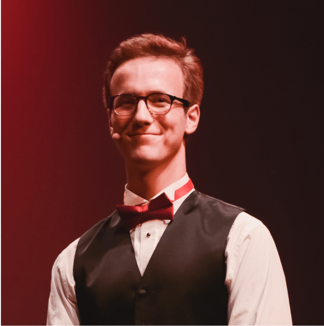 Liam McGregor on stage in a tuxedo under red lighting