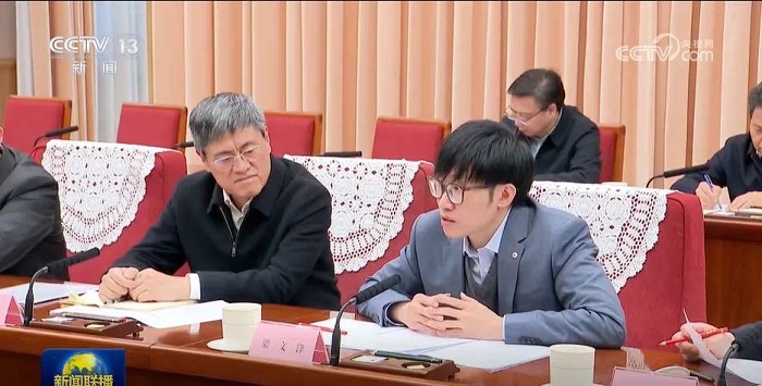 Liang Wenfeng, on the right in a grey jacket, speaks into a microphone at the January 20, 2025 roundtable.