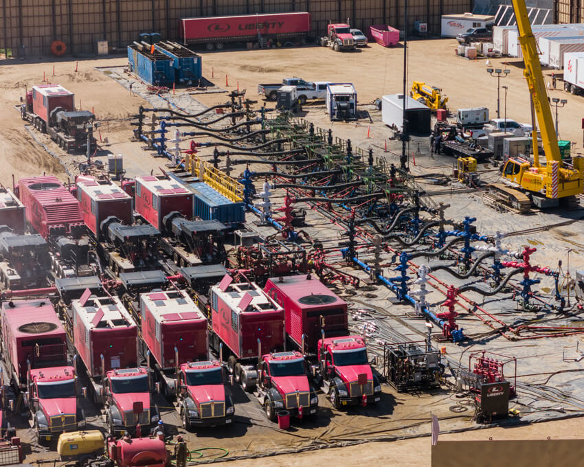 Rows of Liberty frac pumps connected by lines at a busy wellsite