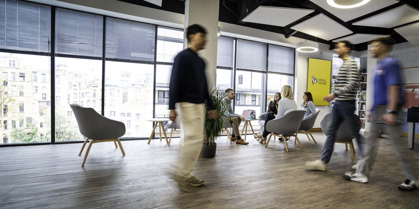Liberty IT employees moving through a bright collaborative office in Belfast